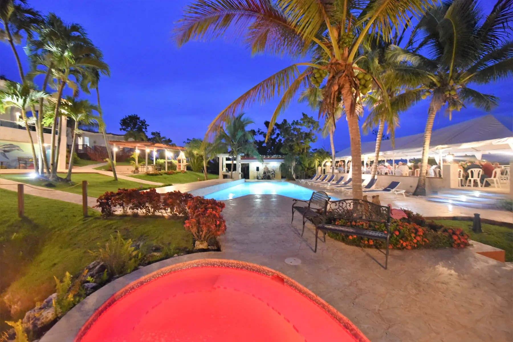 Piscina, jacuzzi y área de eventos iluminados al anochecer